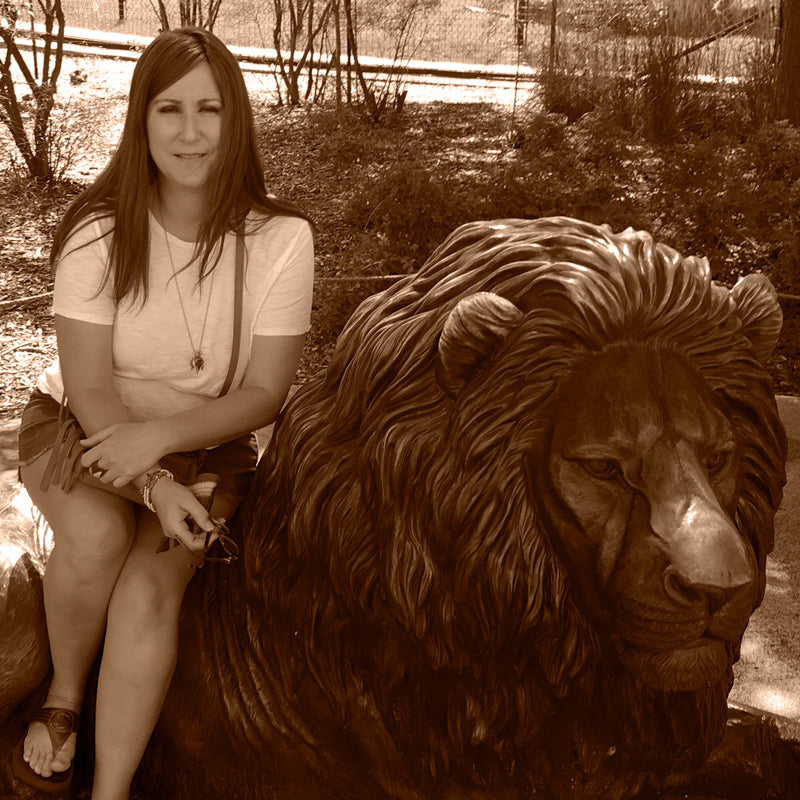 Artist of Spirit Cat sitting on large metal lion